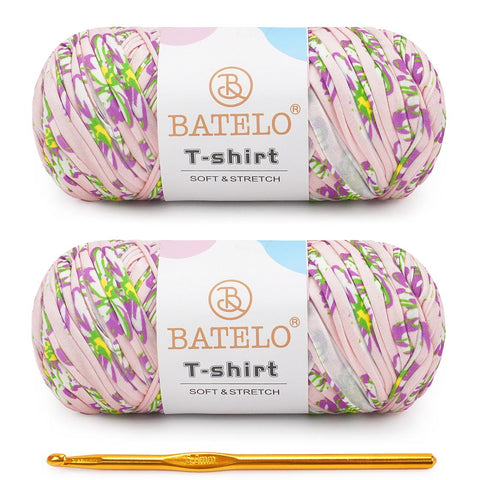 Two green, pink, and lilac variegated BATELO T-shirt yarn skeins with a gold crochet hook on a white background