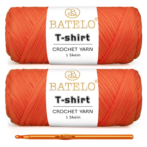 Two orange BATELO T-shirt yarn skeins with a gold crochet hook on a white background