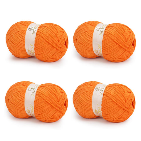 Four orange BATELO bulky chenille blanket yarn skeins arranged on a white background