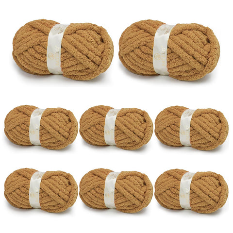 Eight warm tan BATELO chunky chenille yarn skeins arranged on a white background