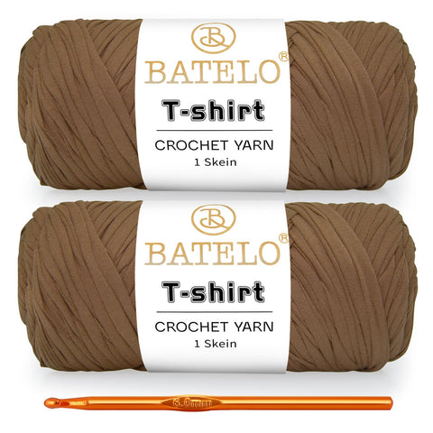 Two tan BATELO T-shirt yarn skeins with a gold crochet hook on a white background