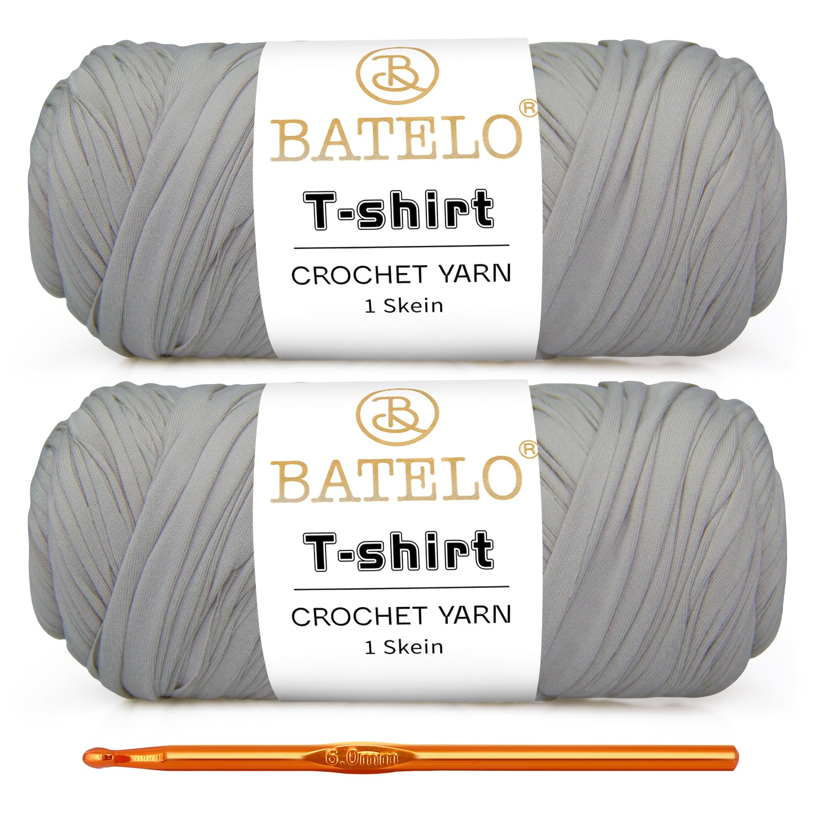 Two light gray BATELO T-shirt yarn skeins with a gold crochet hook on a white background