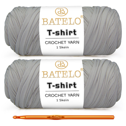 Two light gray BATELO T-shirt yarn skeins with a gold crochet hook on a white background