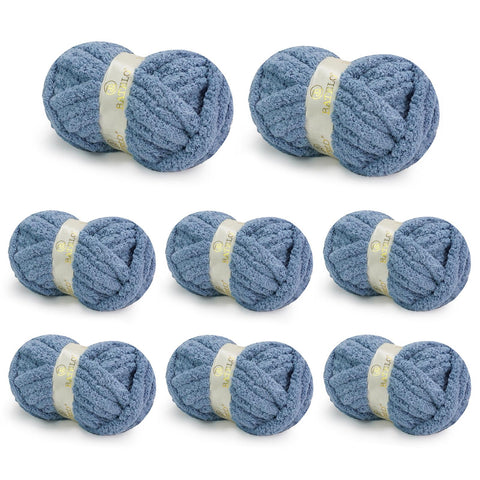 Eight denim blue BATELO chunky chenille yarn skeins arranged on a white background