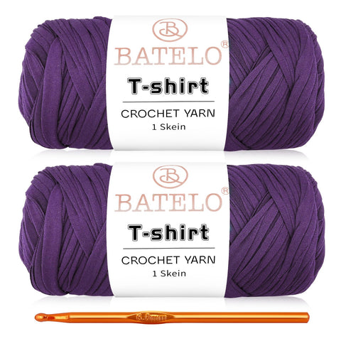 Two purple BATELO T-shirt yarn skeins with a gold crochet hook on a white background
