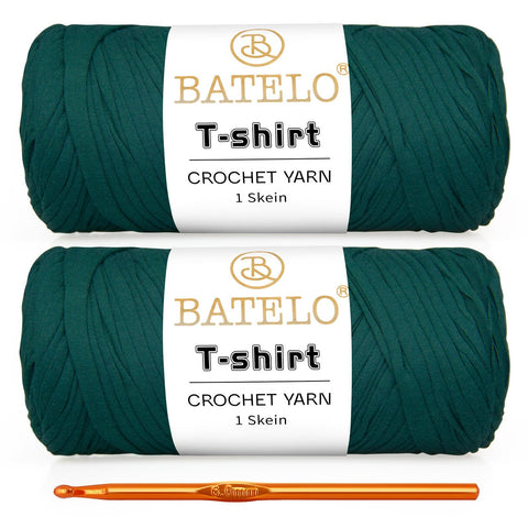 Two dark green BATELO T-shirt yarn skeins with a gold crochet hook on a white background