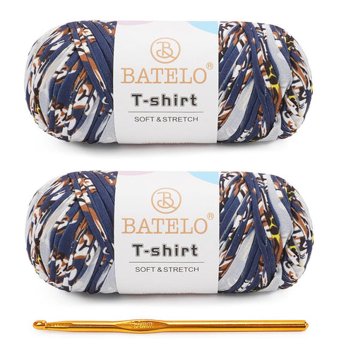 Two navy, tan, and white variegated BATELO T-shirt yarn skeins with a gold crochet hook on a white background