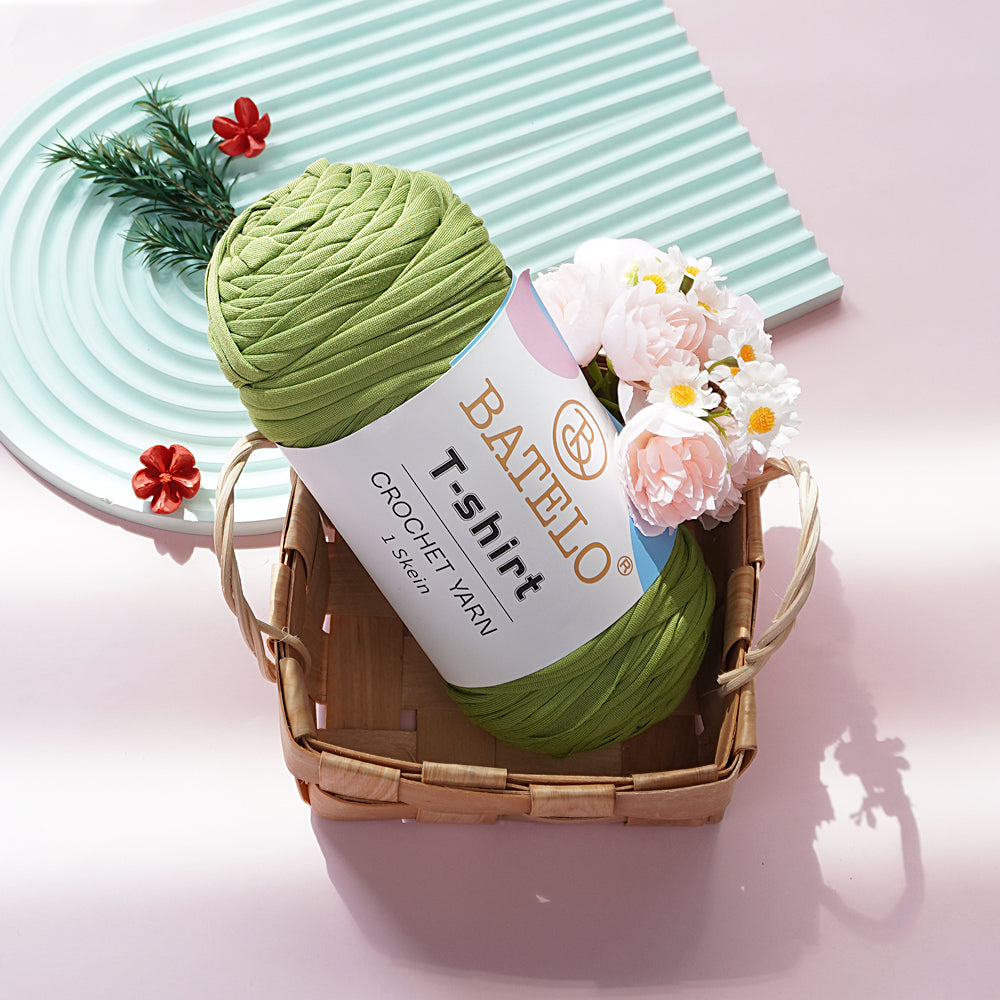 Light Green BATELO T-shirt yarn skein in a wicker basket with flowers on a pink tabletop