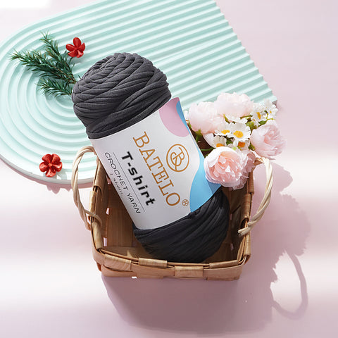Charcoal Gray BATELO T-shirt yarn skein in a wicker basket with flowers on a pink tabletop
