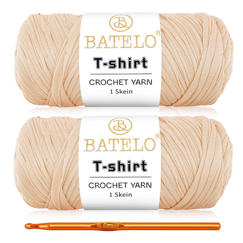 Two peach beige BATELO T-shirt yarn skeins with a gold crochet hook on a white background
