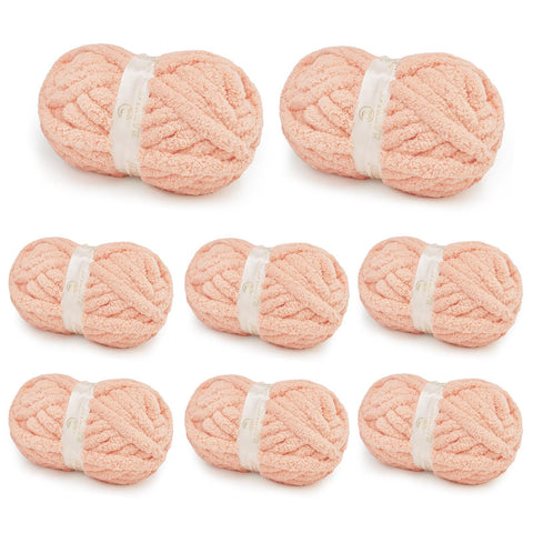 Eight blush peach BATELO chunky chenille yarn skeins arranged on a white background