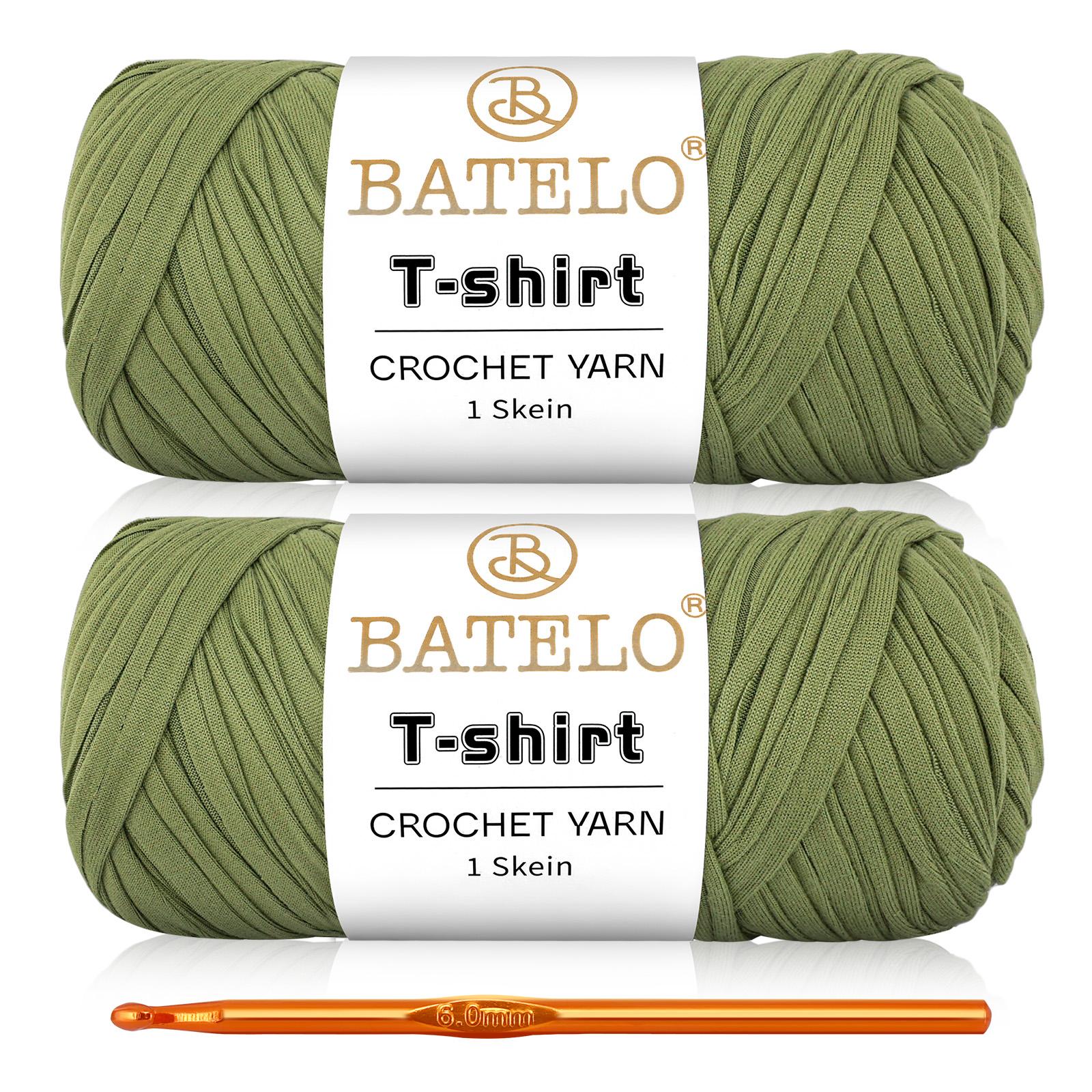 Two olive green BATELO T-shirt yarn skeins with a gold crochet hook on a white background
