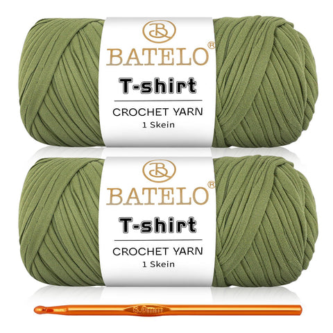 Two olive green BATELO T-shirt yarn skeins with a gold crochet hook on a white background