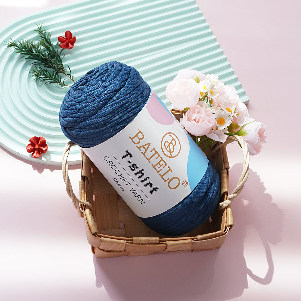 Navy Blue BATELO T-shirt yarn skein in a wicker basket with flowers on a pink tabletop