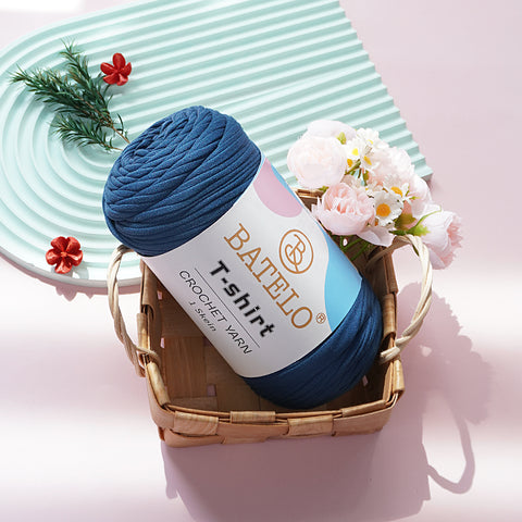 Navy Blue BATELO T-shirt yarn skein in a wicker basket with flowers on a pink tabletop