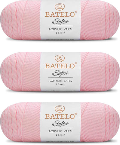 Three blush pink BATELO medium acrylic yarn skeins with white labels on a white background