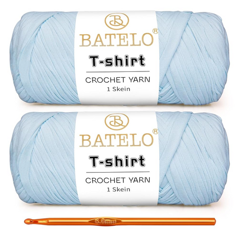 Two light blue BATELO T-shirt yarn skeins with a gold crochet hook on a white background