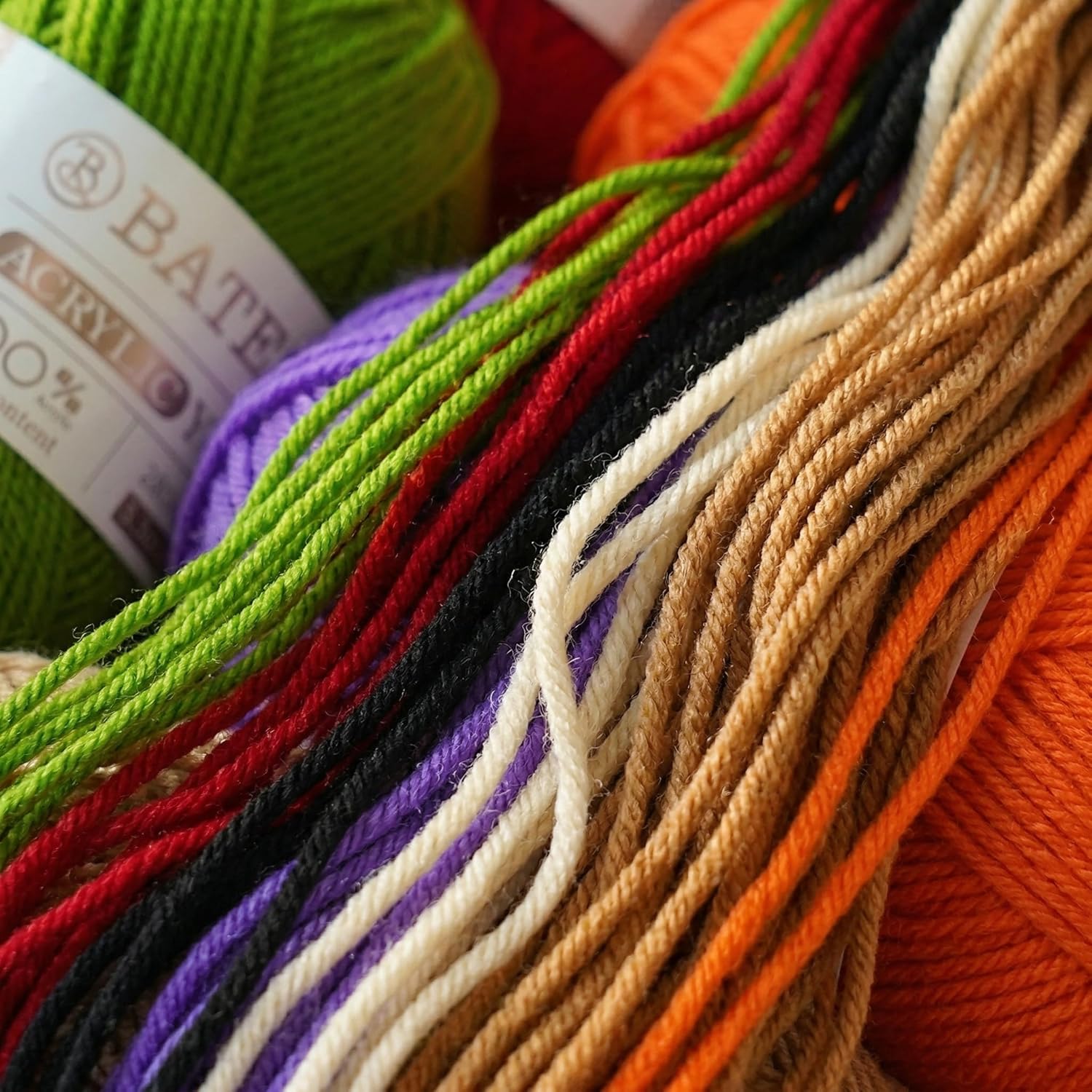 Close-up bundle of acrylic yarn strands in green, purple, red, black, orange, and beige
