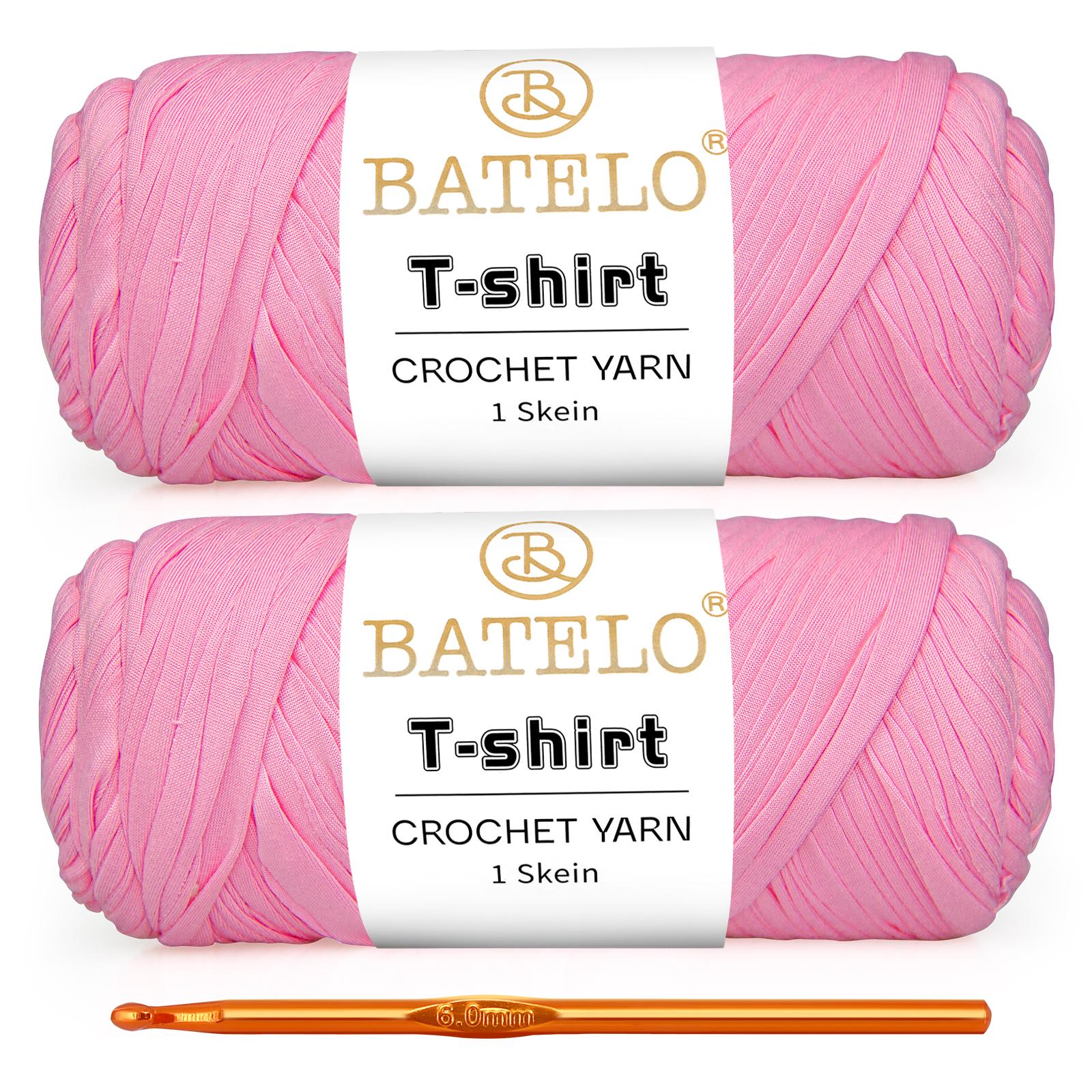 Two soft pink BATELO T-shirt yarn skeins with a gold crochet hook on a white background