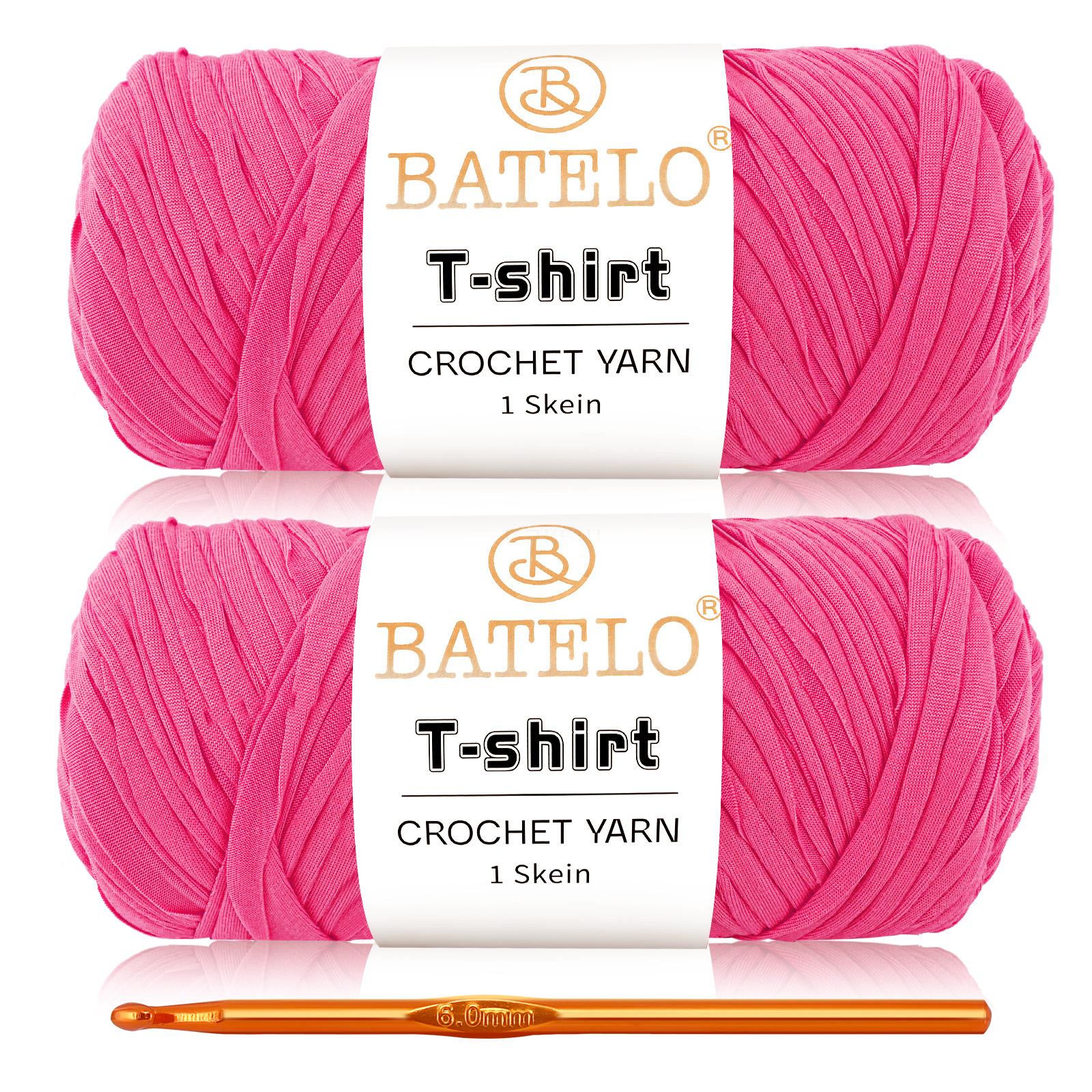 Two hot pink BATELO T-shirt yarn skeins with a gold crochet hook on a white background