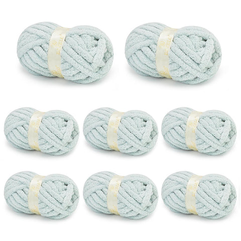 Eight pale blue BATELO chunky chenille yarn skeins arranged on a white background