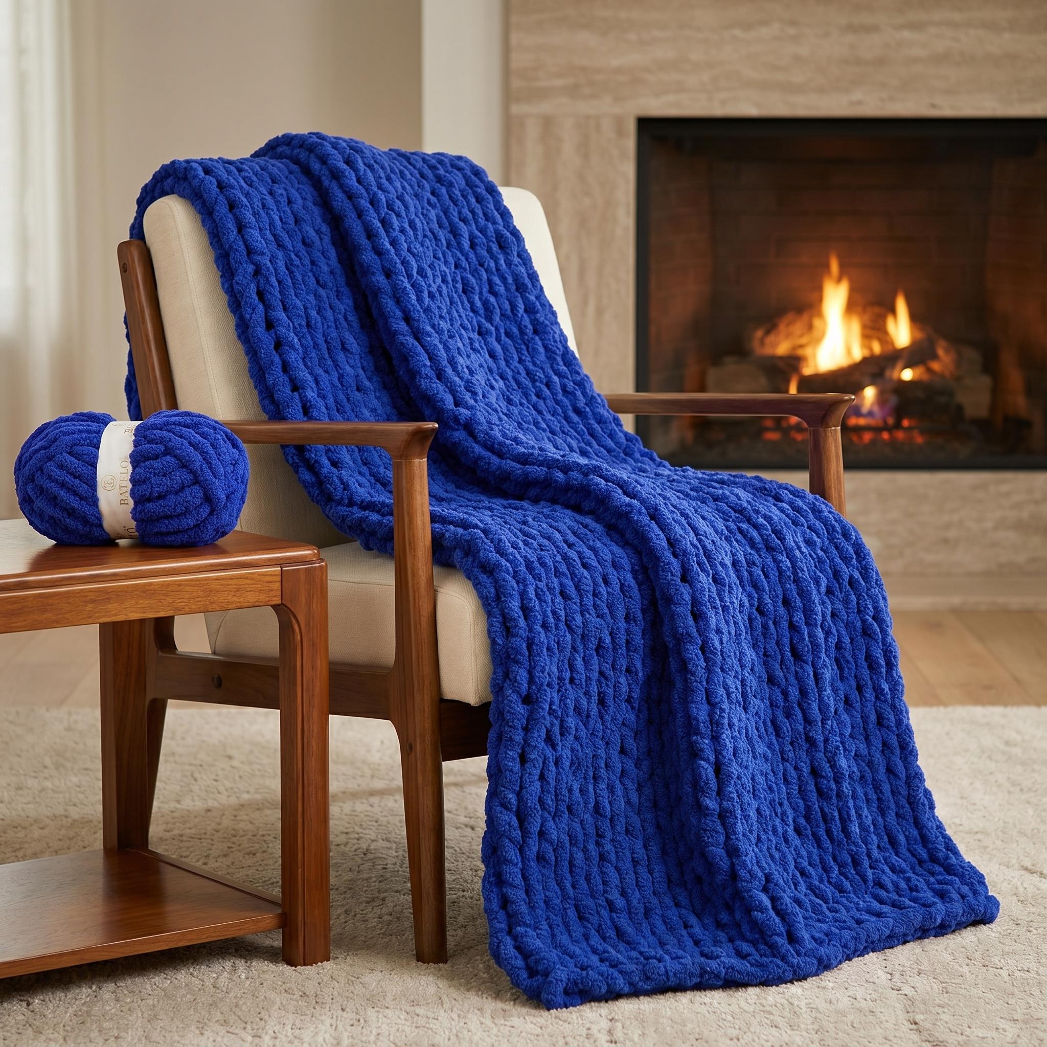 Royal Blue chunky chenille knit blanket draped over a wooden chair beside a lit fireplace