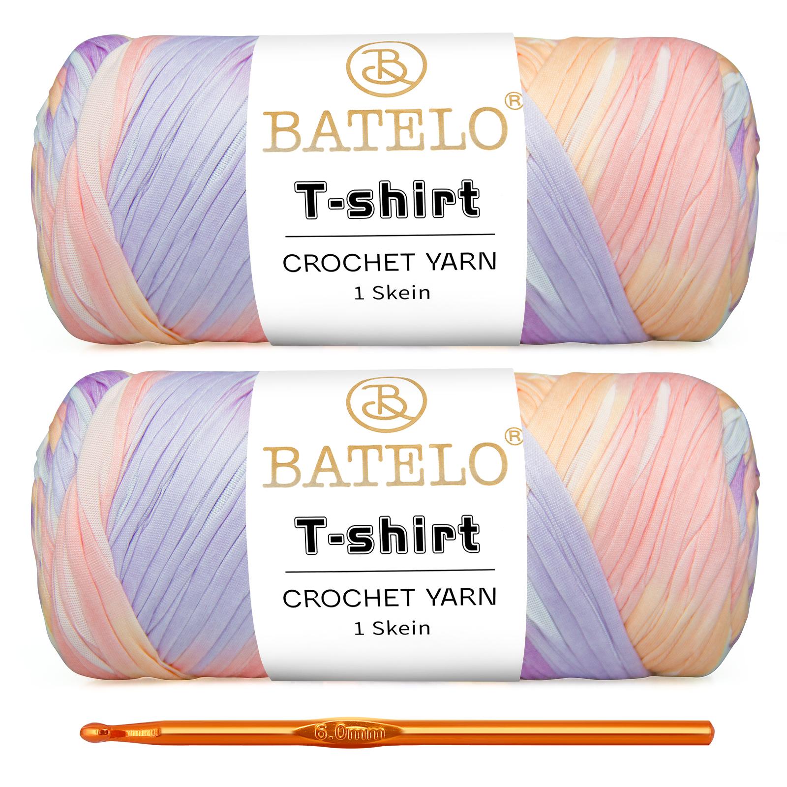Two pastel pink, lavender, and peach variegated BATELO T-shirt yarn skeins with a gold crochet hook on a white background