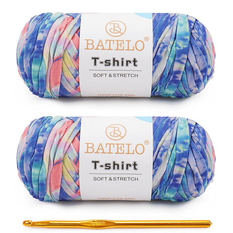 Two blue, pink, and purple variegated BATELO T-shirt yarn skeins with a gold crochet hook on a white background